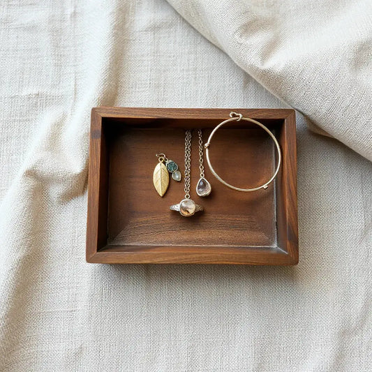 Assorted eco-friendly jewelry on a wooden tray with natural stones and soft linen fabric in warm light