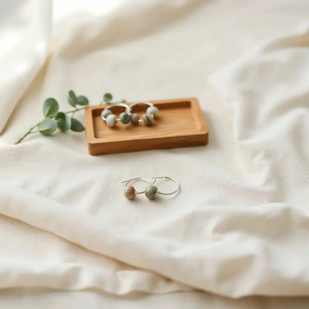 Eco-friendly hoop earrings and a small pendant necklace with natural stone beads on linen.