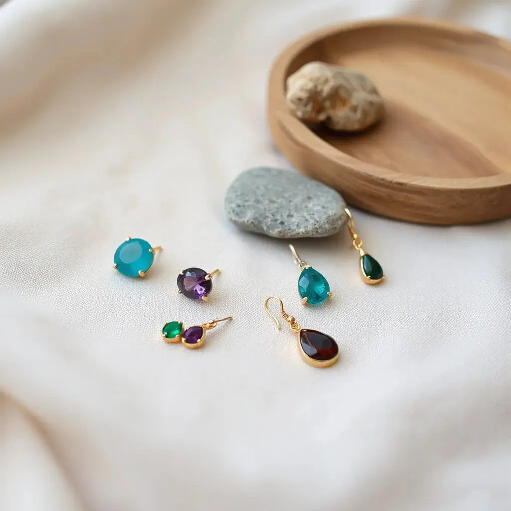 Assorted gemstone earrings with colorful stones on a neutral fabric background