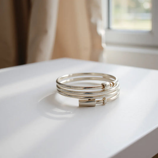 Silver tone cuff bracelets arranged on a neutral surface with soft natural light