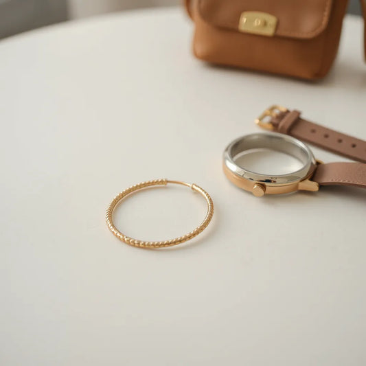Gold hoop earrings on a neutral surface with soft studio lighting and minimal styling