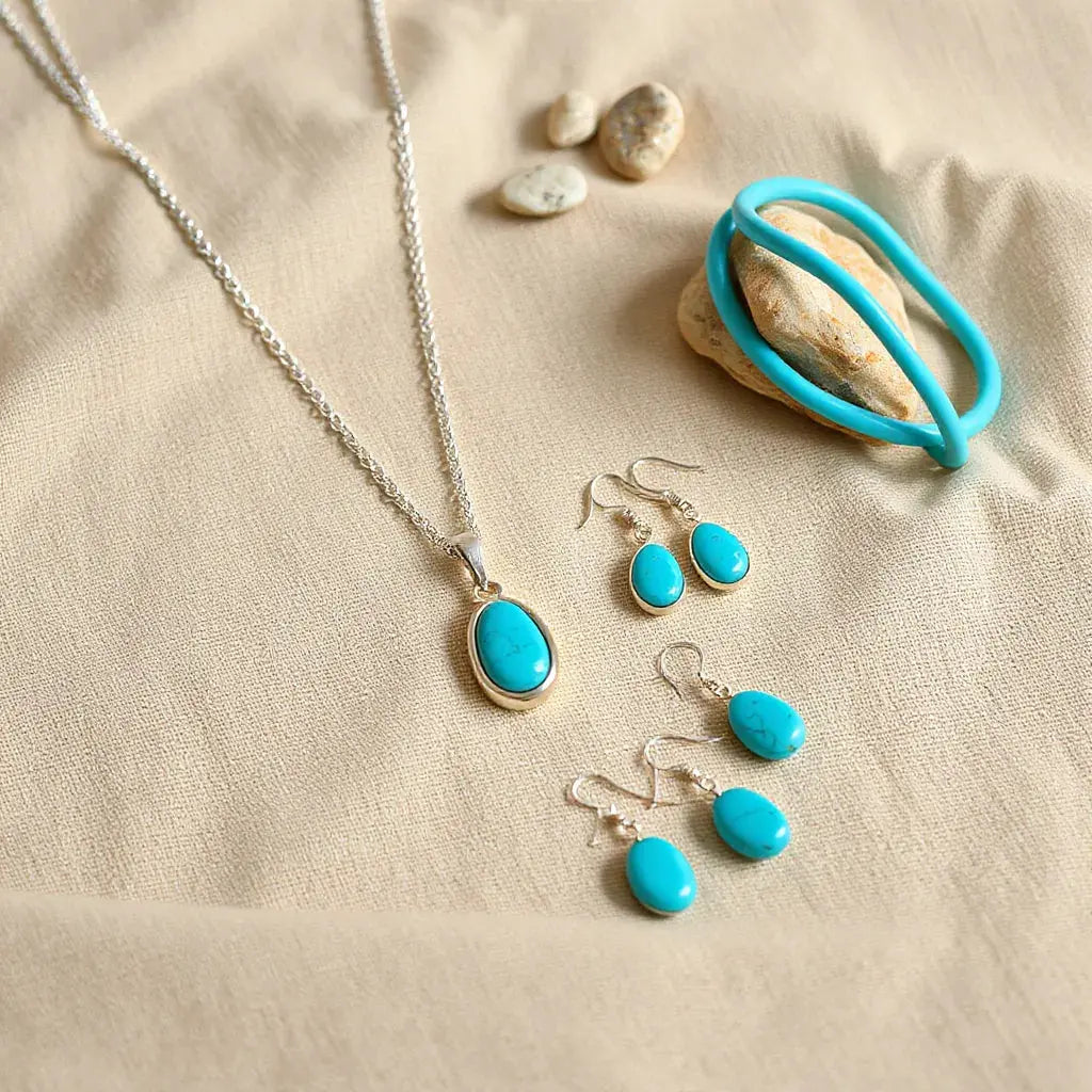 Silver Navajo-style jewelry set with turquoise pendant necklace, drop earrings, and cuff bracelet on neutral fabric