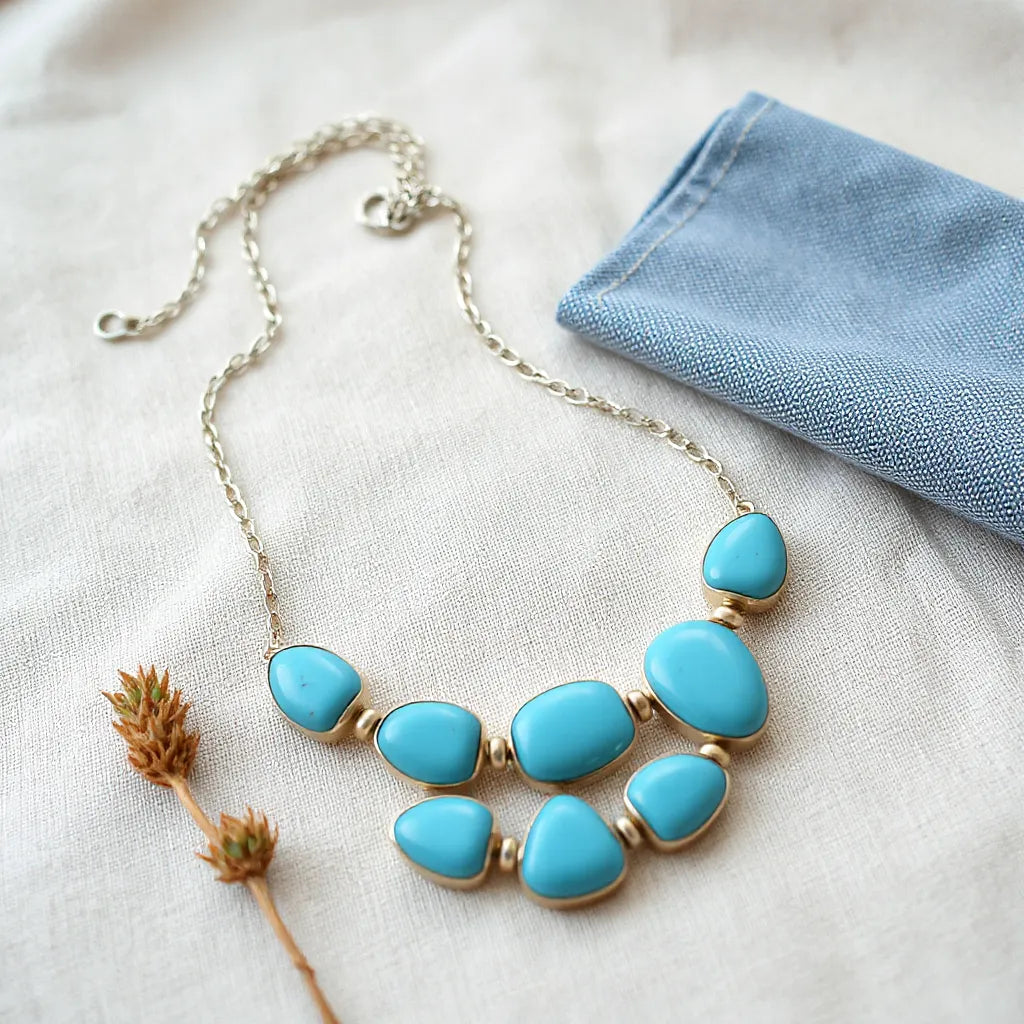 Turquoise necklace with visible stones and silver chain on neutral fabric