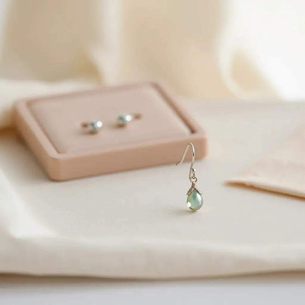 Hypoallergenic stud and drop earrings resting on a neutral background with visible metal finishes