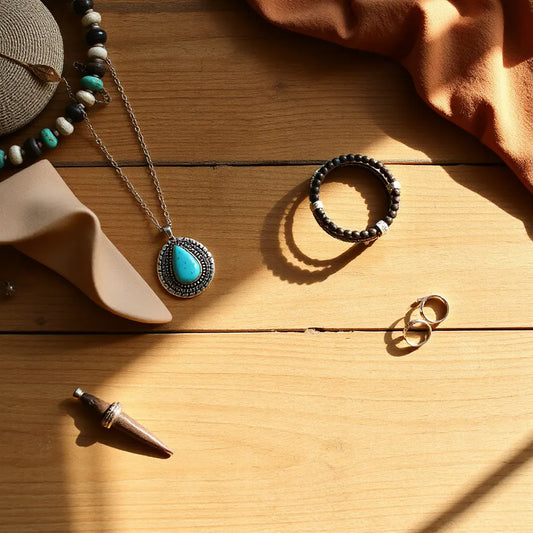 Curated Western boho accessories on a wooden table with turquoise jewelry and leather accents
