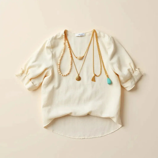 Layered boho necklaces with beads and pendants on a neutral linen blouse