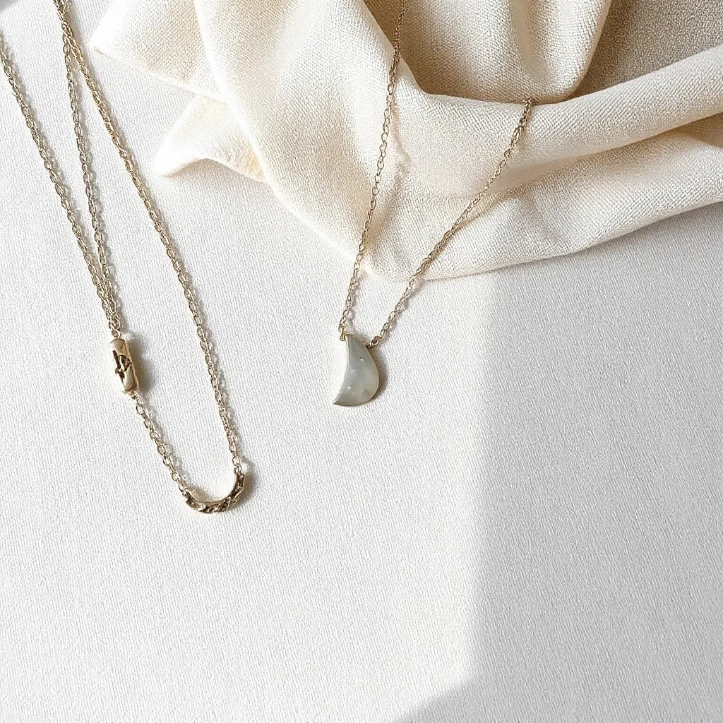 Sterling silver necklaces with delicate chains and small pendants displayed on neutral fabric