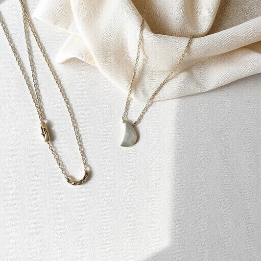 Sterling silver necklaces with delicate chains and small pendants displayed on neutral fabric