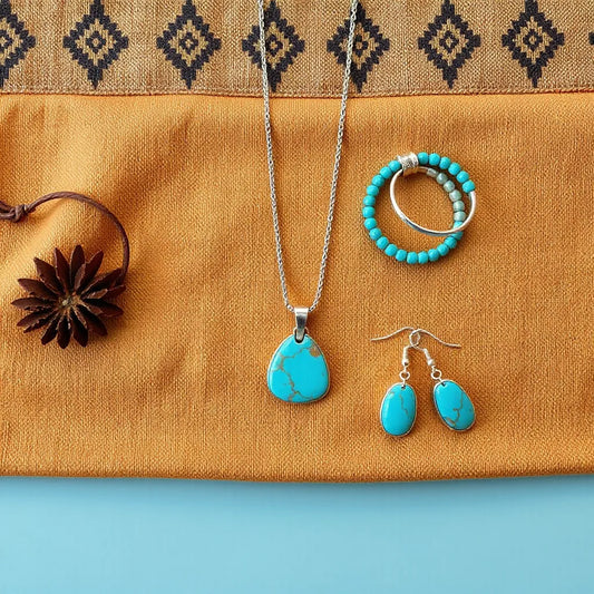 Turquoise pendant necklace with stacked beaded bracelets and small earrings on desert fabric