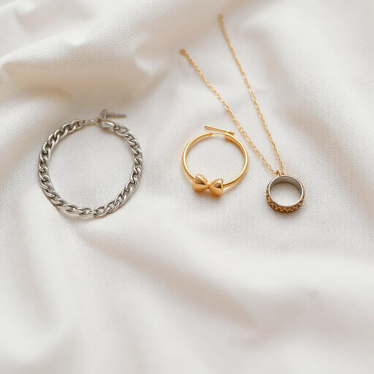 Silver and gold jewelry pieces arranged on neutral fabric with soft natural light