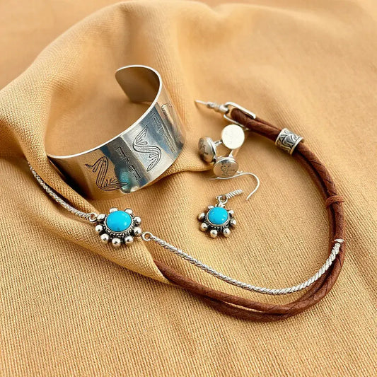 Stamped silver and turquoise native American style jewelry set on neutral fabric