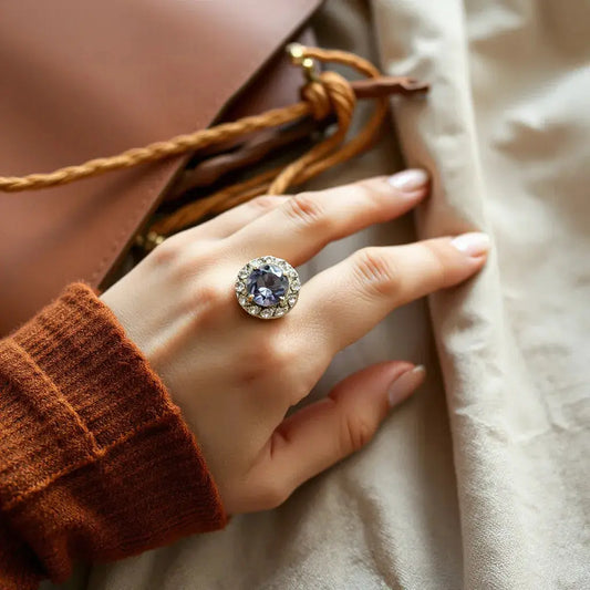 Hand holding a warm boho palette with a bold statement ring featuring a prominent gemstone setting