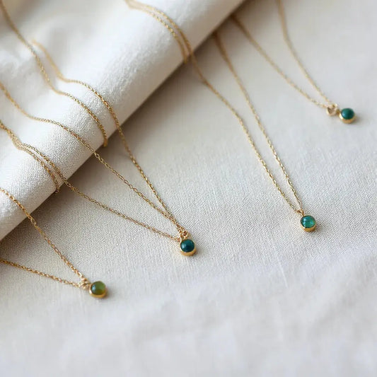 Handcrafted necklaces with delicate pendants and subtle stones arranged on neutral linen under soft light