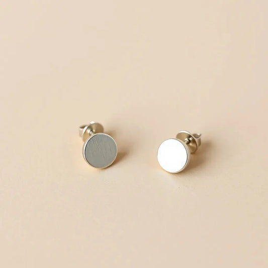 Pair of hypoallergenic earrings with visible ear-safe metal posts on a neutral studio background