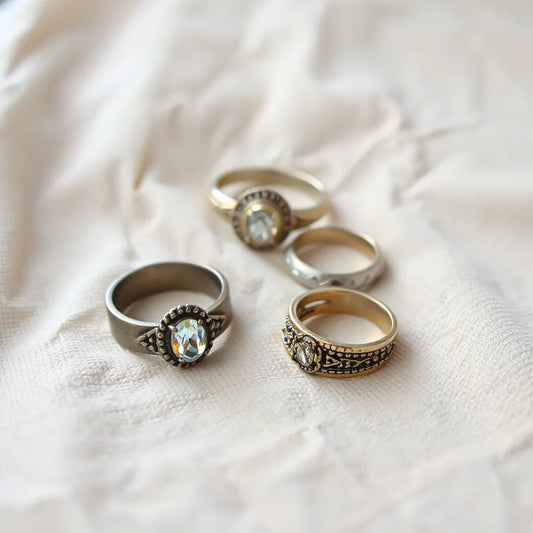 Vintage inspired rings laid out in a stack on neutral linen fabric with soft window light